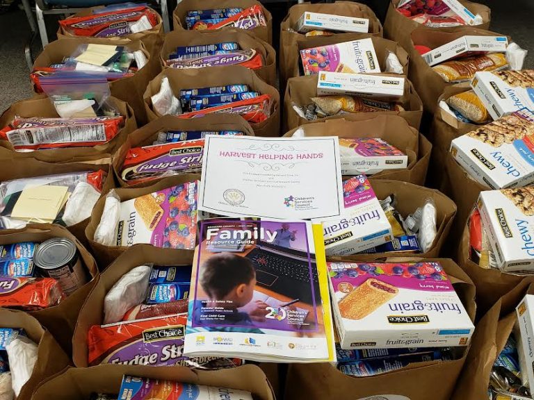 Grocery bags of crackers and snacks with a family resource guide and Harvest Helping Hands card
