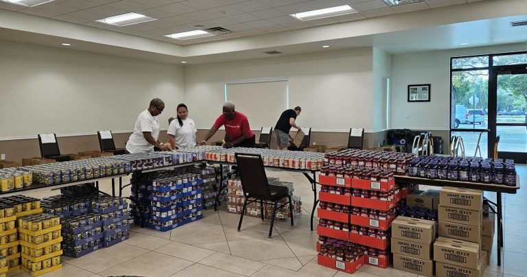 Volunteers lining up jars and cans along tables across a large hall