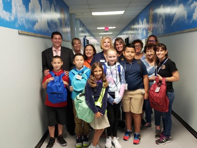 Country Isles Elementary School children with new backpacks lined up in a hallway with a sky mural