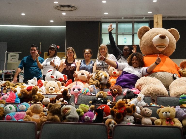 Volunteers behind auditorium seats filled with stuffed animals and a giant teddy bear at the Western High School Boutique