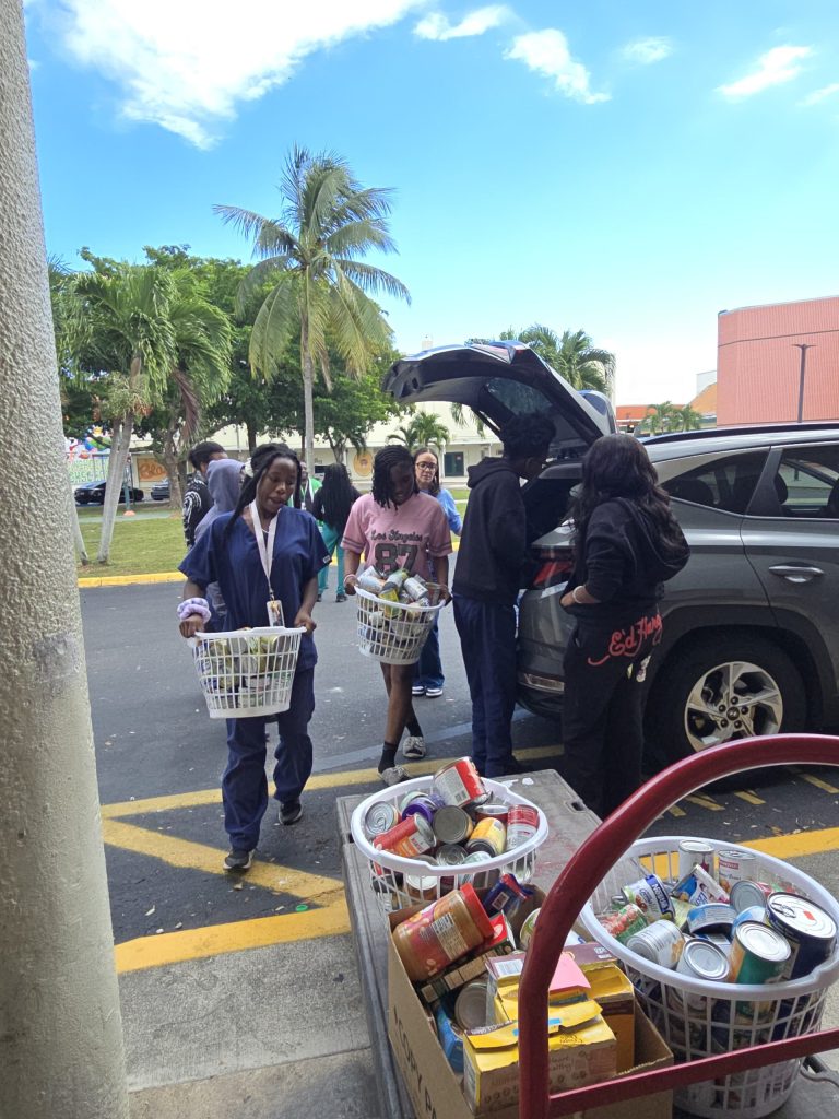 Blanche Ely High School students unloading donated groceries from a car trunk into baskets and carts