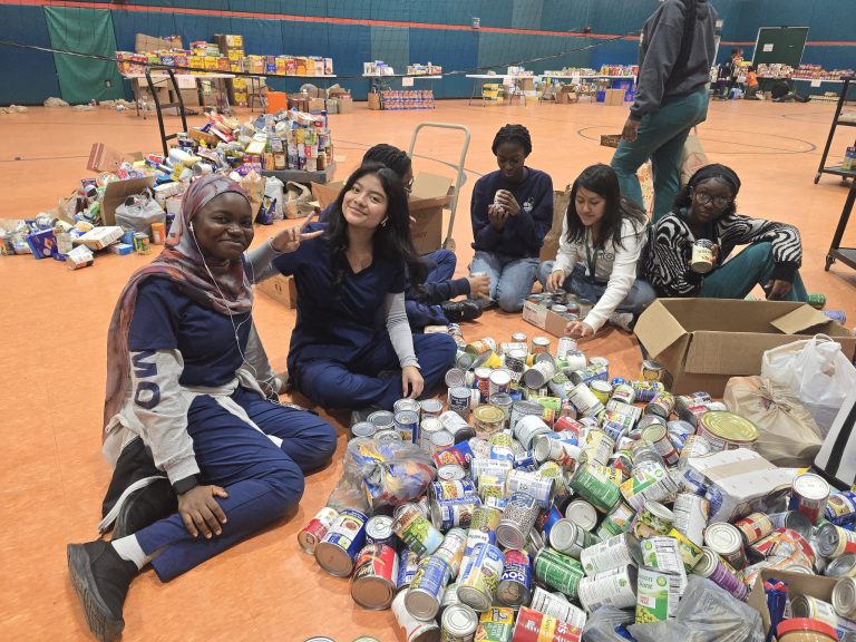 Blanche Ely High School students sitting on the gym floor surrounded by piles of canned goods