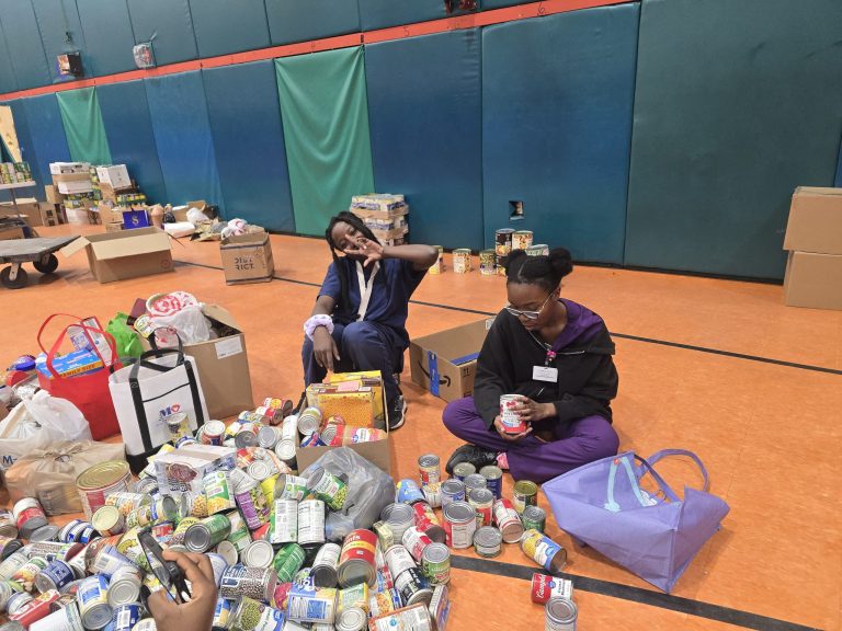 Blanche Ely High School students sorting cans and bags of donations on the orange gym floor