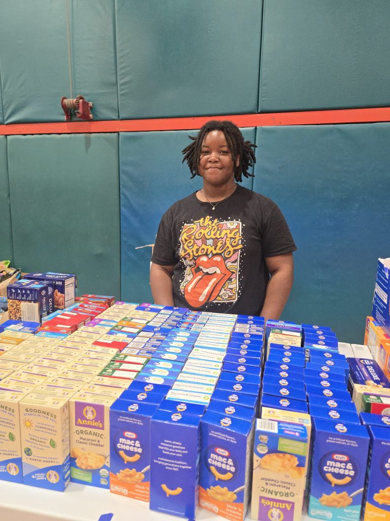 Blanche Ely High School student standing behind rows of macaroni and cheese boxes