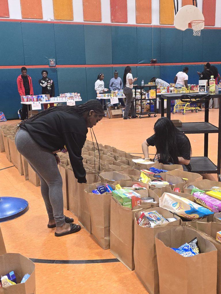 Blanche Ely High School students packing long rows of brown paper bags on the gym floor