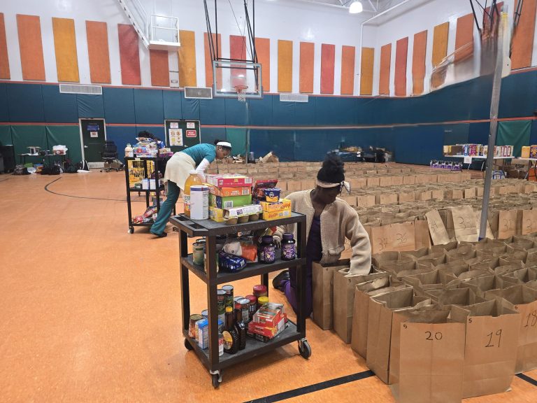 Blanche Ely High School volunteers filling rows of numbered paper bags from a food cart in the gym