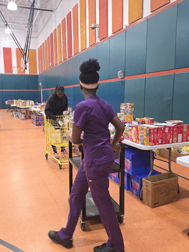 Blanche Ely High School student pushing a cart past tables of donated food in the gym
