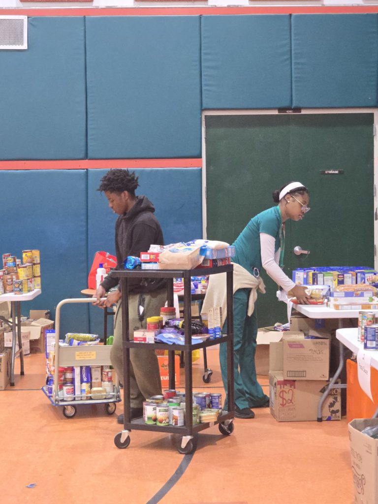 Blanche Ely High School students loading food onto a rolling cart near the gym tables