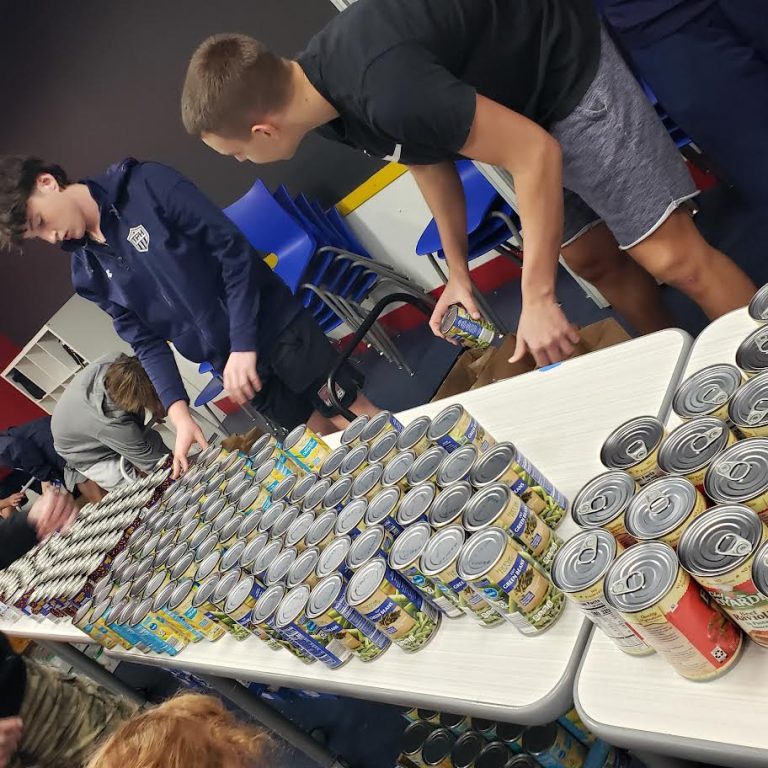 Teens arranging rows of canned goods on tables