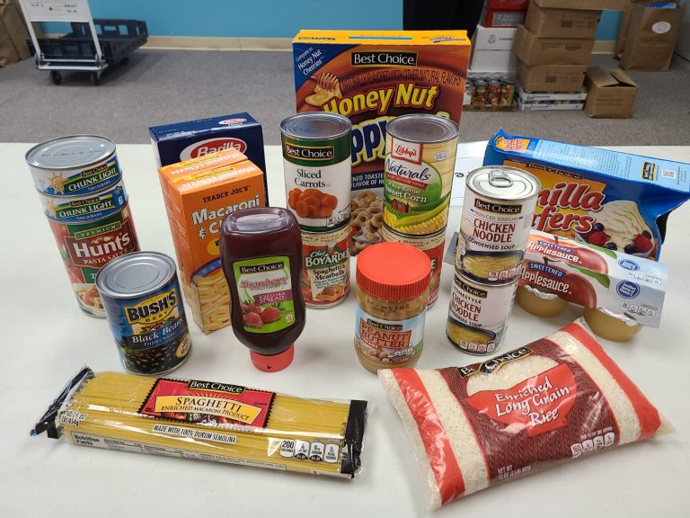 Sample grocery items including canned goods, pasta, rice, cereal and peanut butter on a table, Monthly Bag Packings