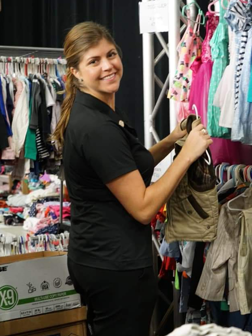 Volunteer arranging clothes on hangers at a rack in the Harvest Drive Boutique