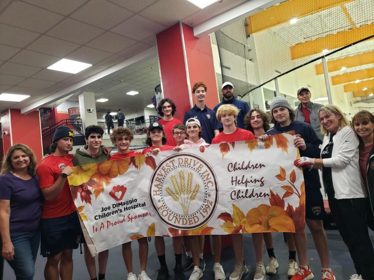 Large group of teens and adults holding a Harvest Drive banner sponsored by Joe DiMaggio Children's Hospital