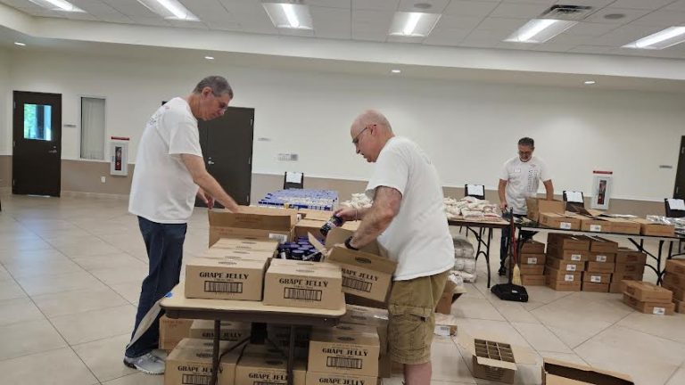 Volunteers opening boxes of grape jelly on long tables at Monthly Packings