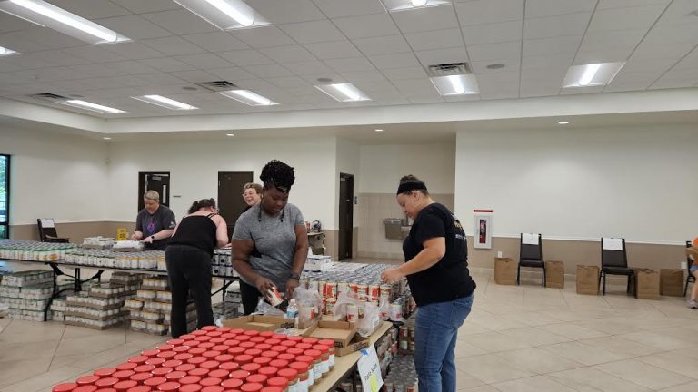 Volunteers filling bags at tables crowded with jars of peanut butter at Monthly Packings