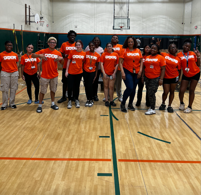 McArthur High School students in orange shirts posing in the gym for a group photo