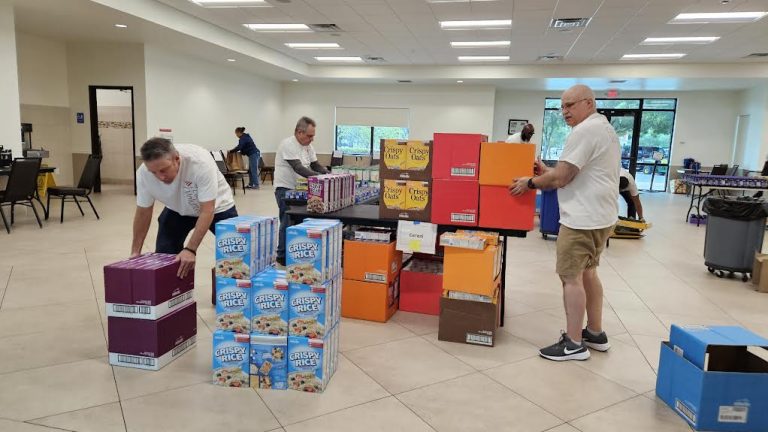 Volunteers stacking cases of cereal and snack boxes onto a cart at Monthly Packings