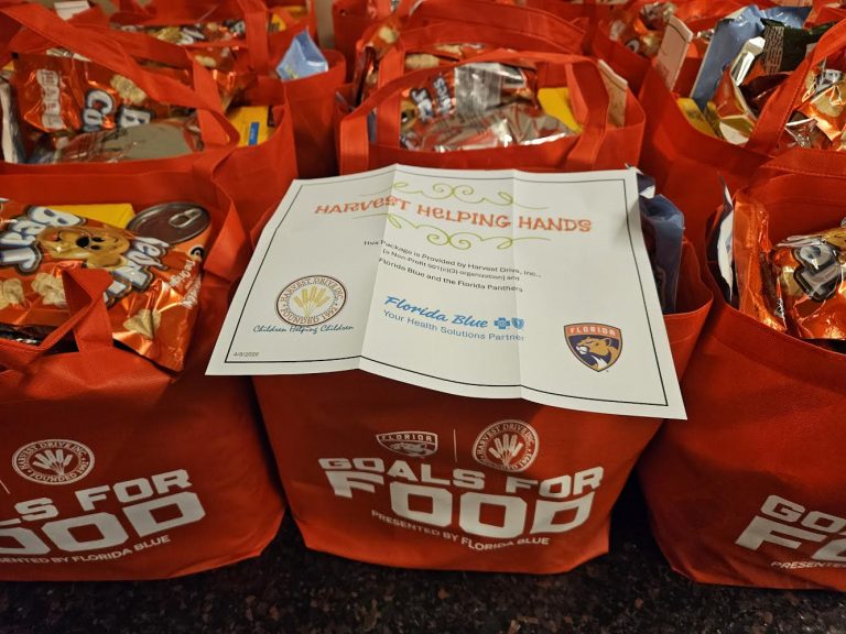 Goals for Food tote bags with a Harvest Helping Hands sign naming Florida Blue and the Florida Panthers