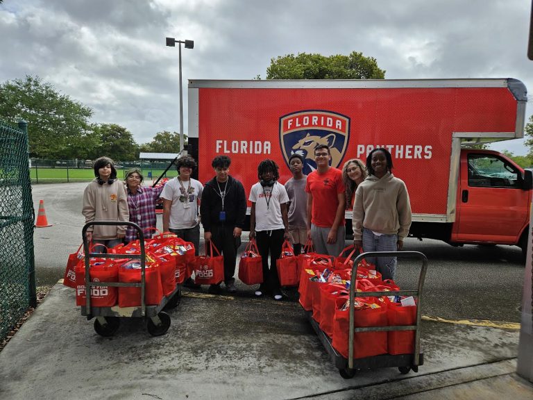 Students with carts of red tote bags in front of a Florida Panthers truck