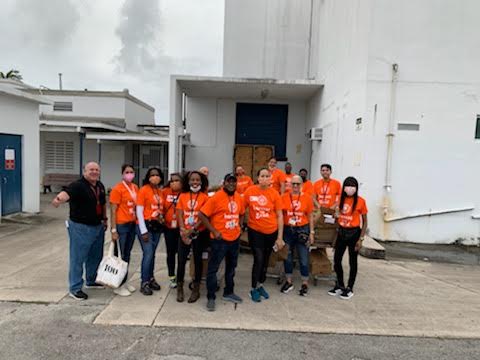 Pompano Beach High School volunteers in orange shirts gathered outside a school building