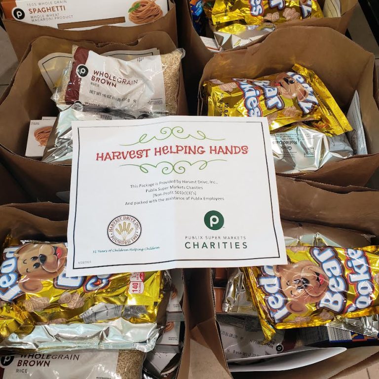 Bags of rice and cookies topped with a Harvest Helping Hands card noting Publix Super Markets Charities