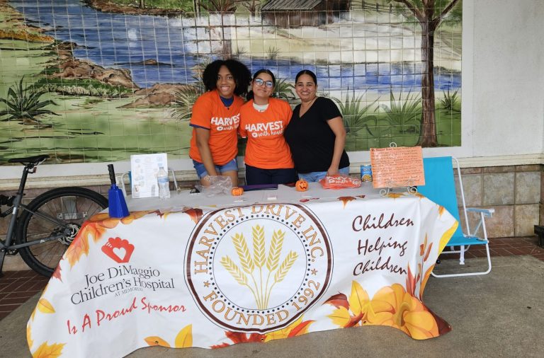 Western High School students at a Harvest Drive table draped with a "Children Helping Children" banner
