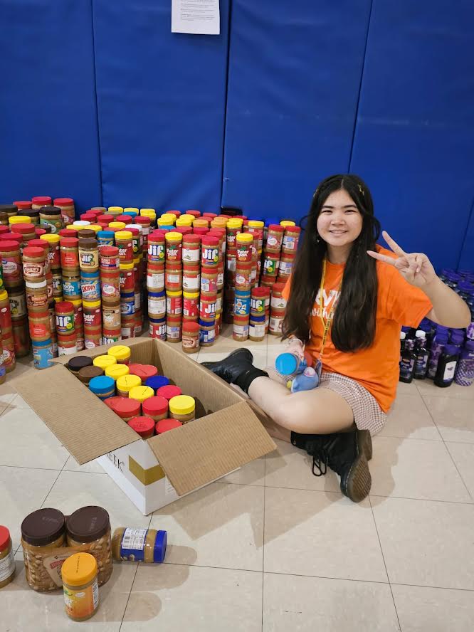 Westglades Middle School student sitting on the floor beside towers of peanut butter jars